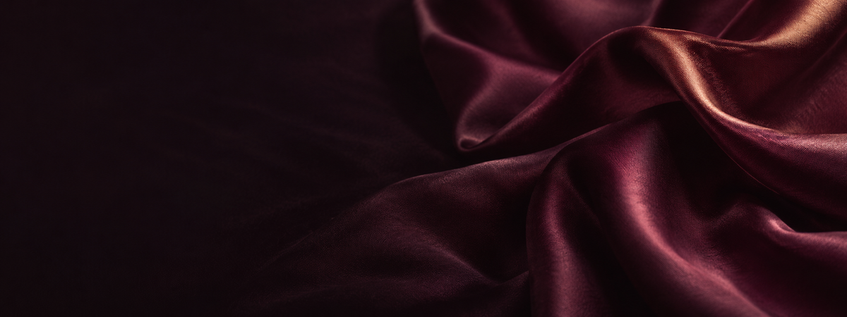 Folds of deep plum silk lit from one side in warm copper light